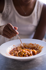 Image showing a young African American woman eating pasta