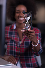 Image showing young woman at office looking at sand  clock