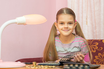 Image showing The child leafing through an album for collectors of coins and looked into the frame