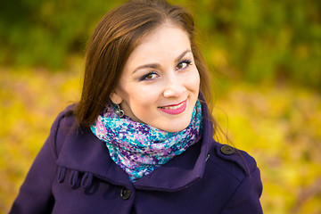 Image showing Portrait of a smiling beautiful girl on the blurry background of autumn leaves