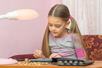 Image showing The child looks at a coin album for collectibles