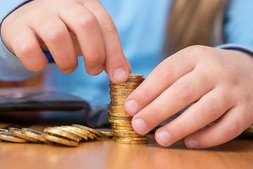 Image showing Child collects a stack of golden coins, close-up