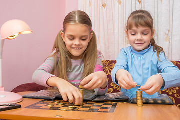 Image showing Two children build towers of coins