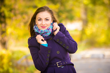 Image showing Girl in a dark blue coat against the background of autumn leaves