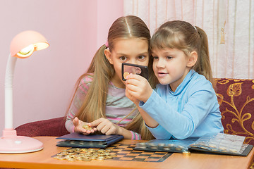 Image showing Two children looking at a coin through a magnifying glass