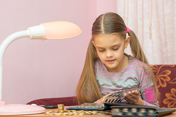 Image showing Carried away by the girl leafing through the album for collecting coins