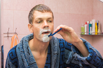 Image showing Young man shaving in front of mirro