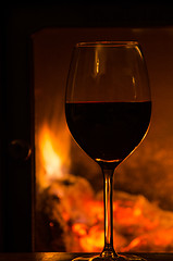 Image showing Glowing fire with a glass of red wine