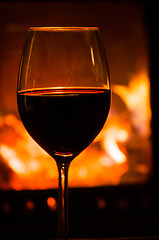 Image showing Glass of red wine and fireplace