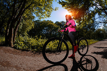 Image showing Young woman having fun riding a bicycle in the park.