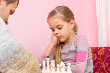 Image showing Seven-year daughter is thinking about the next move, playing chess