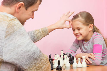 Image showing Dad won a game of chess at a daughter on a bet and hit her on the head