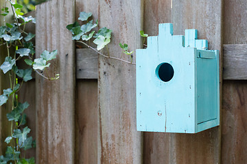 Image showing Blue birdhouse on a wooden fence