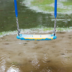 Image showing Plastic swing hanging over a puddle