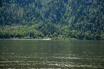 Image showing boat goes along the shore of a mountain lake