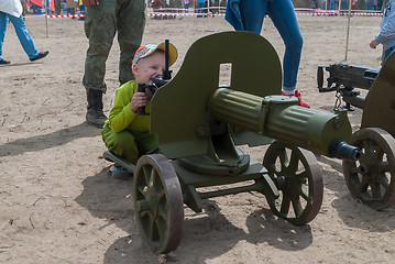 Image showing The boy considers an old easel machine gun