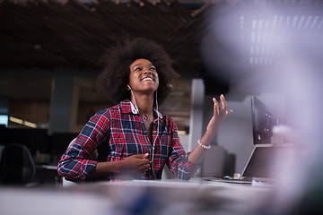 Image showing woman at her workplace in startup business office listening musi