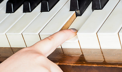 Image showing Young unrecognizable girl child, playing piano by pressing down 