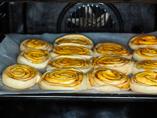 Image showing Closeup of raw cinnamon buns after proofing with egg yolk, on ba