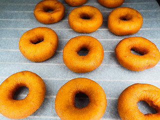 Image showing Closeup of freshly made dark brown doughnuts on baking paper