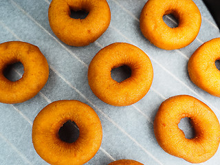 Image showing Closeup of freshly made dark brown doughnuts on baking paper