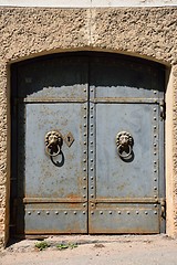 Image showing Old iron door with lion handles on a stone wall