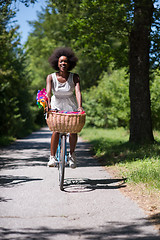 Image showing pretty young african american woman riding a bike in forest