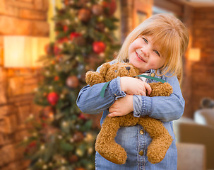 Image showing Girl Holding Teddy Bear In Front of Decorated Christmas Tree