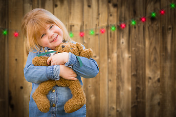 Image showing Girl Holding Teddy Bear In Front of Wooded Background with Chris