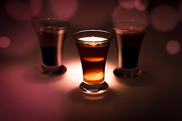 Image showing red and tow shot glass on a dark background in the spot light