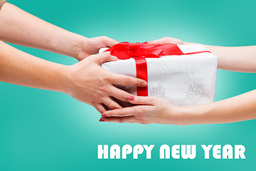 Image showing Female and male hands holding gift on blue background