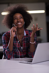Image showing black woman in modern office at her workplace speeking on phone 
