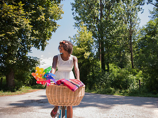 Image showing pretty young african american woman riding a bike in forest