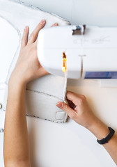 Image showing Girl tailoring fabric on sewing-machine