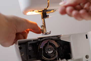 Image showing Seamstress prepares sewing-machine to work