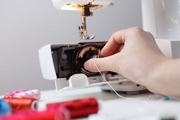 Image showing Woman inserts bobbin in sewing-machine