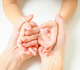 Image showing Toddlers hands in fathers hands, towards, on a white table