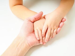 Image showing Toddlers hands in fathers hand, towards, on a white table