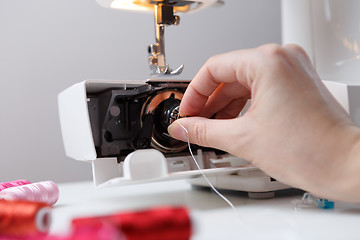 Image showing Girl inserts bobbin in sewing-machine