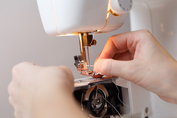 Image showing Seamstress inserts thread in sewing-machine