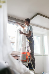 Image showing Plasterer renovating indoor walls and ceilings. Construction finishing works.