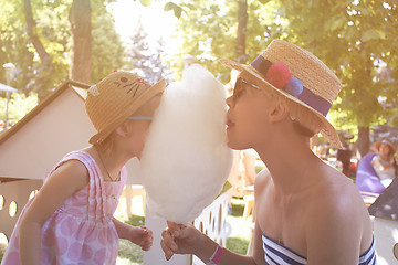 Image showing Child eats cotton candy with mom in city street