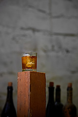 Image showing Glass of whiskey with ice on old wooden bar
