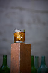 Image showing Glass of whiskey with ice on old wooden bar