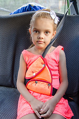Image showing A child of six sitting in the back seat of the car and strapped in using a restraint device