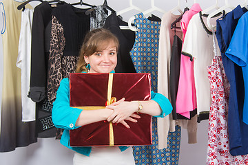 Image showing Happy young girl has received a welcome gift in the background hang things on hangers