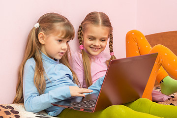 Image showing Two girls play computer games on a laptop