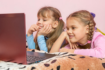 Image showing Sisters lying on bed looking at laptop cartoon