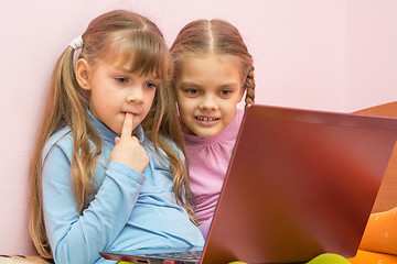 Image showing Funny girl put a finger in his mouth sitting at a laptop