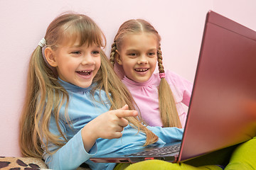 Image showing Two girls looking at a laptop and laughing merrily, one is pointing at the screen